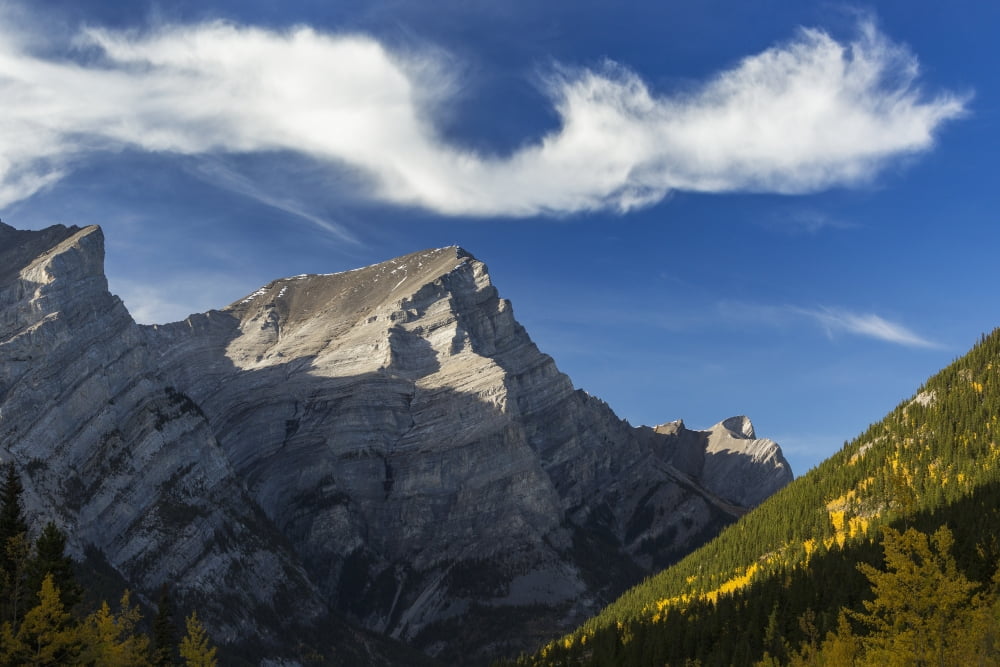 Close up of mountain peak lit by the sun in an alpine valley with autumn colours and an interesting cloud formation and blue sky Kananaskis Provincial Park Alberta Canada Canvas Art - Michael Interisa