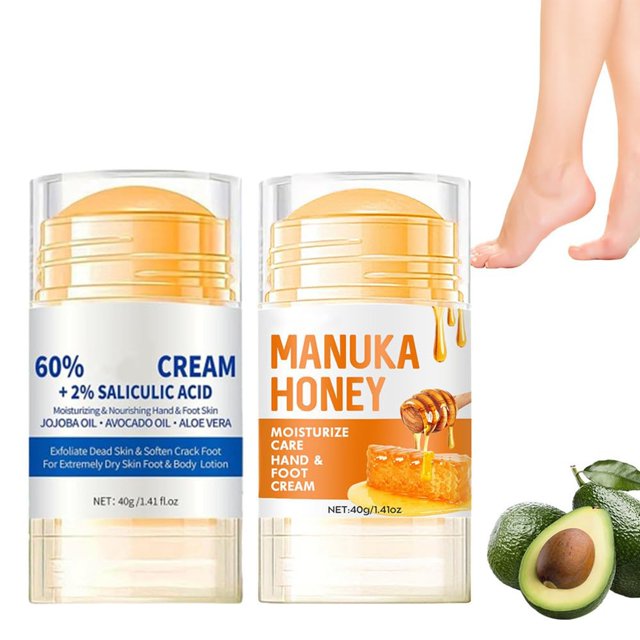 crema hidratante para pies agrietados | reparadora de talones agrietados | hidratante y calmante | crema para manos y pies (2 unidades) Vista frontal de dos sticks transparentes con bálsamo beige; el izquierdo muestra texto azul '60% CREAM + 2% SALICYLIC ACID', el derecho muestra 'MANUKA HONEY' con imagen de miel; aguacate y gotas de miel en la esquina inferior y pies descalzos recortados en la esquina superior derecha sobre fondo blanco; también indicada para manos muy secas.