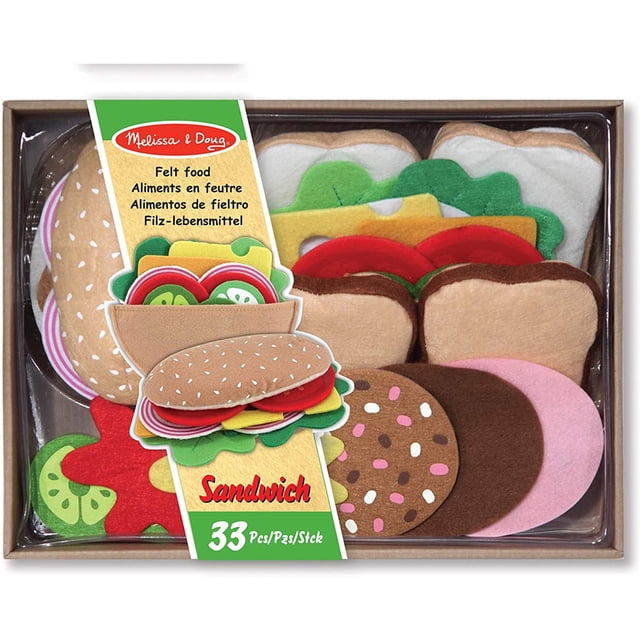 set para preparar sandwich de fieltro melissa y doug 33 pza caja con piezas organizadas en vista cenital: dos panes cafés con semillas, rodajas de tomate y pepino en fieltro, hojas de lechuga verde, lonchas de queso amarillo y de jamón rosa, galleta marrón con chispas y accesorios; apto para juego simbólico de 3 a 7 años y suele usarse también para actividades educativas de clasificación.