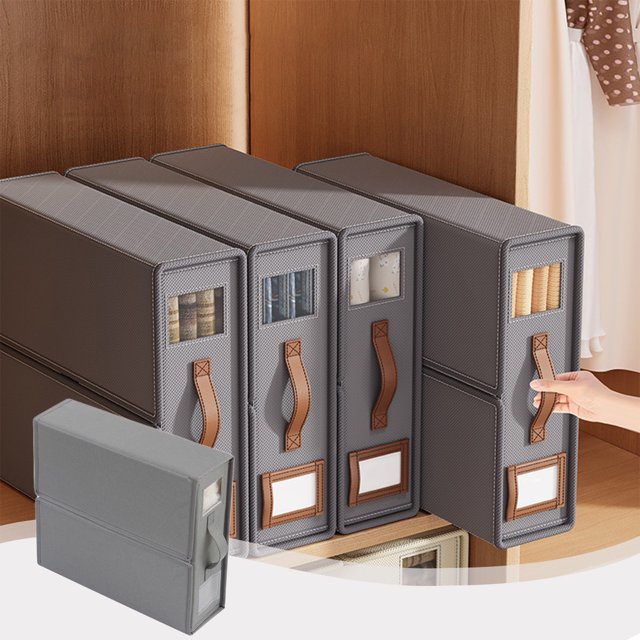 fiudx caja de almacenamiento plegable de gran capacidad color Fresno, vista 3/4 frontal de varias unidades tipo archivador en un clóset; cuerpo rectangular en tela no tejida con costuras visibles, asa frontal en imitación piel, ventana transparente para ver contenido y recuadro para etiqueta inferior, mano tirando de una unidad. Adecuada para organizar ropa y documentos y ahorrar espacio en guardroperos y clósets.