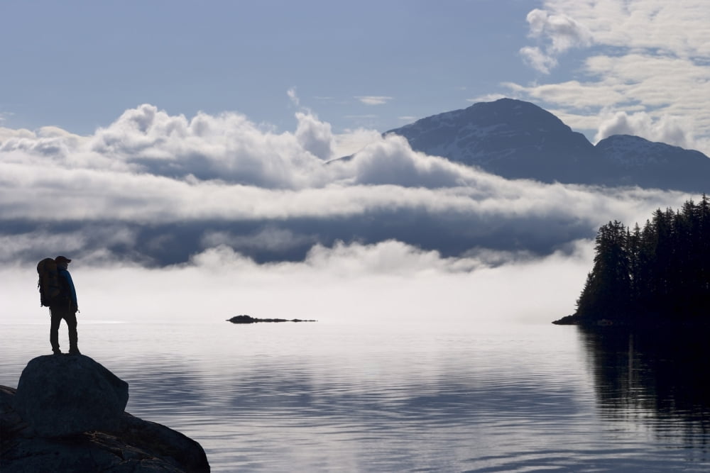 Composite Silhouette Of A Backpacker Along The Shoreline Of Lynn Canal Near Juneau With Chilkat Mountains In The Background Tongass National Forest Inside Passage Alaska Canvas Art - John Hyde Design