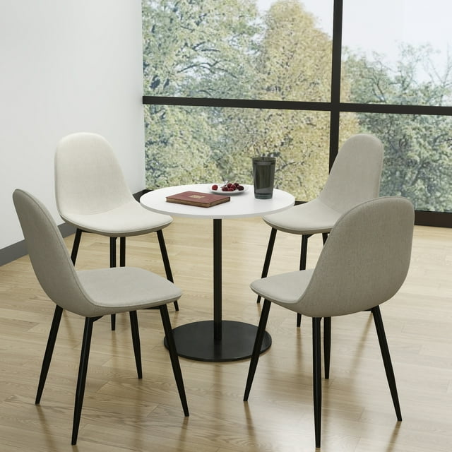 Set of four modern beige fabric side chairs with black metal legs around a small round white table, suitable for conference rooms or home offices.