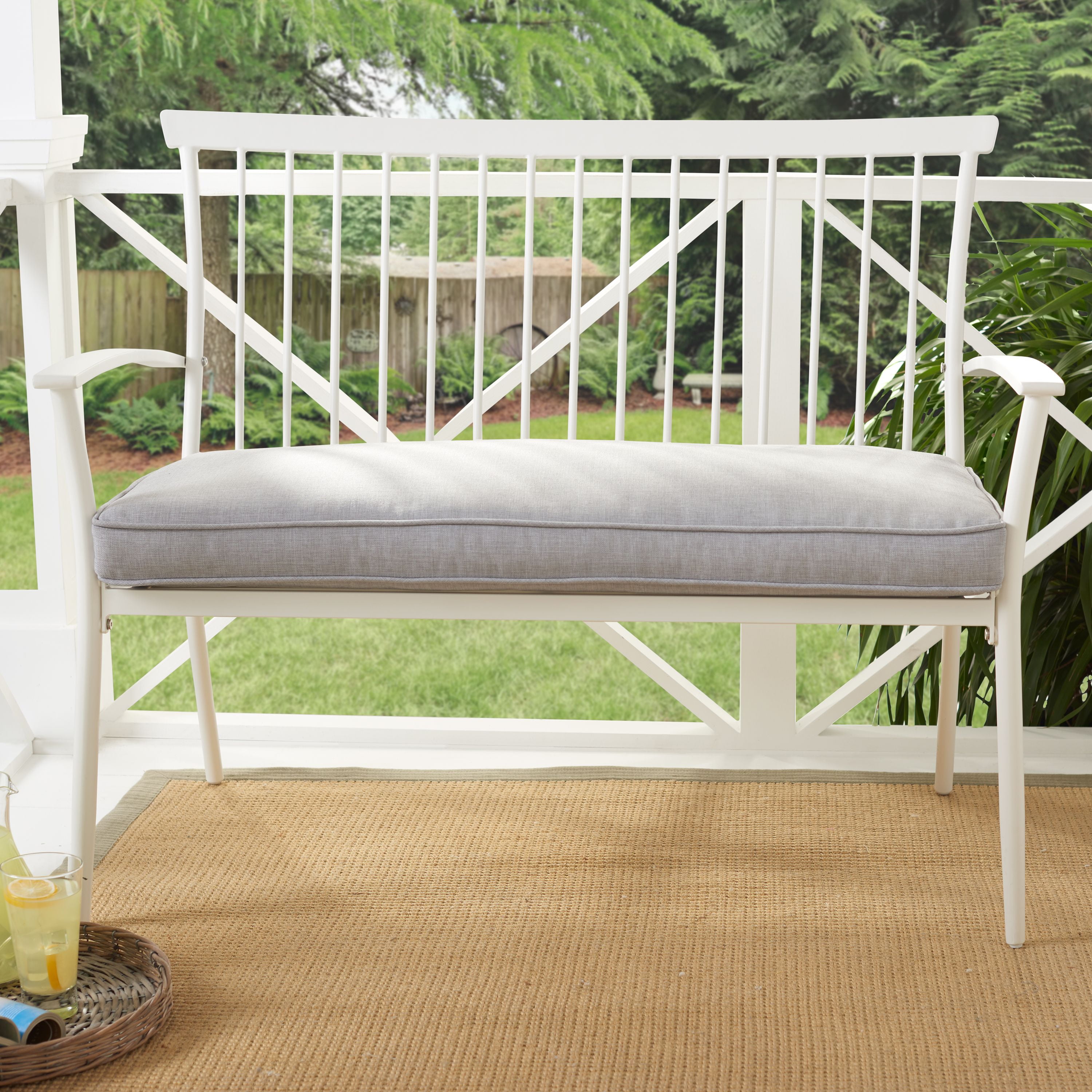 Image of White metal patio bench with cushioned seat