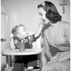 Baby boy sitting in high chair feeding mother with cookie Poster Print