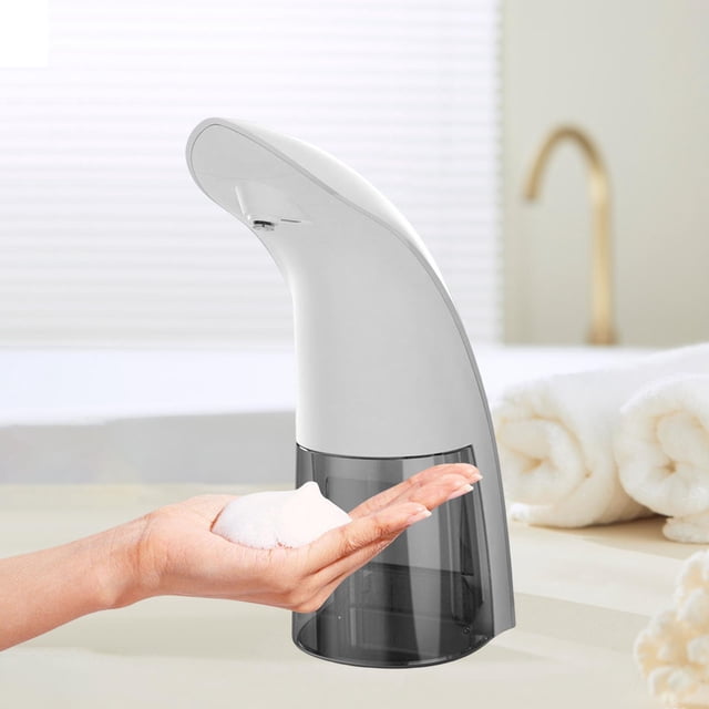 dispensador automático de jabón soledad sin contacto para cocina y restaurante blanco, vista frontal 3/4 con depósito traslúcido gris y boquilla superior; sensor infrarrojo activado y espuma blanca dispensada en la palma de la mano; superficie lisa blanca, tamaño compacto 9 x 2.8 x 21.3 cm; también suele usarse para dispensar loción en áreas de servicio.