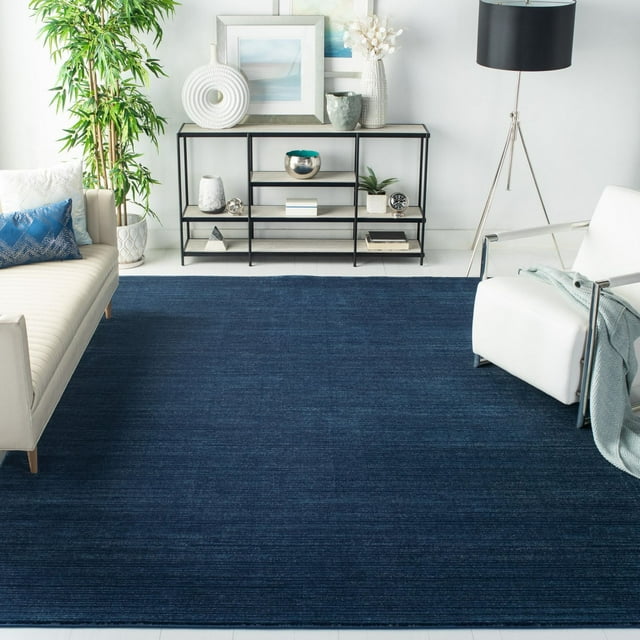 Safavieh Vision Adrasteia overdyed solid navy blue area rug displayed in a contemporary living room with white furniture and decorative accents.