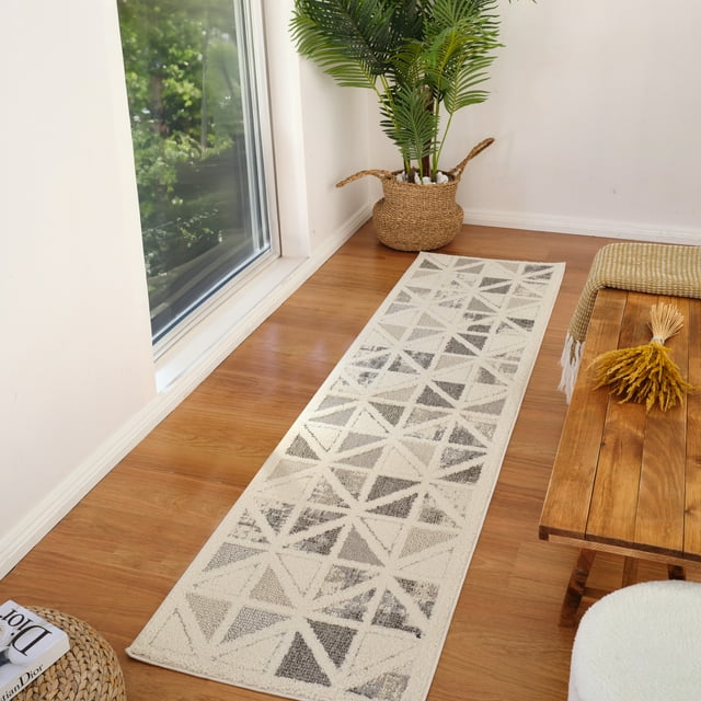 Modern cream and grey geometric indoor area rug runner on wood floor next to window, wicker basket with green plant, and rustic wooden bench in bright living space.