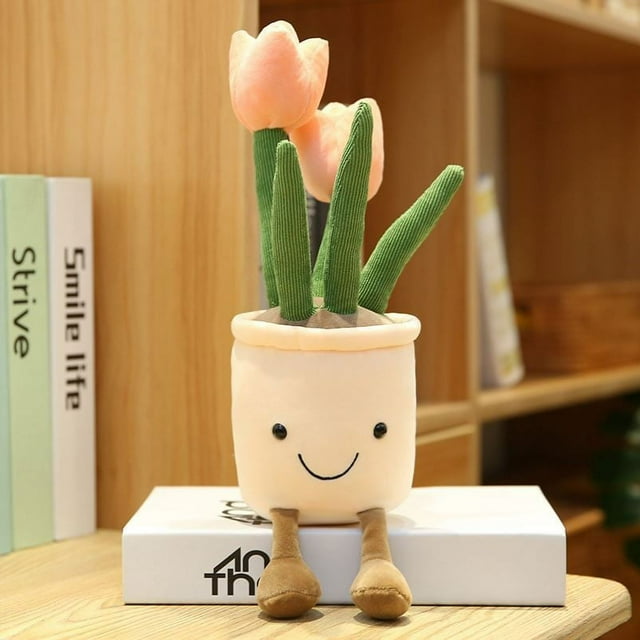 adornos suculentos creativos, juguetes de peluche, simulación divertida, plantas en macetas de tulipán, decoraciones para el hogar, estudio, sala de estar, 35 cm peluche tulipán de 35 cm con maceta beige y carita bordada; tallos verdes de tejido acanalado y dos flores rosa pálido, felpa suave y relleno de algodón PP, vista frontal centrada sobre un libro en estantería doméstica. Adecuado para decorar dormitorio o como regalo para niños y aficionados a los peluches.