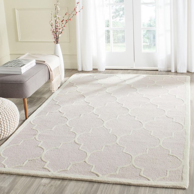 Safavieh Cambridge Kevin light beige geometric pattern area rug on wooden floor in a sunlit room with white curtains and modern decor.