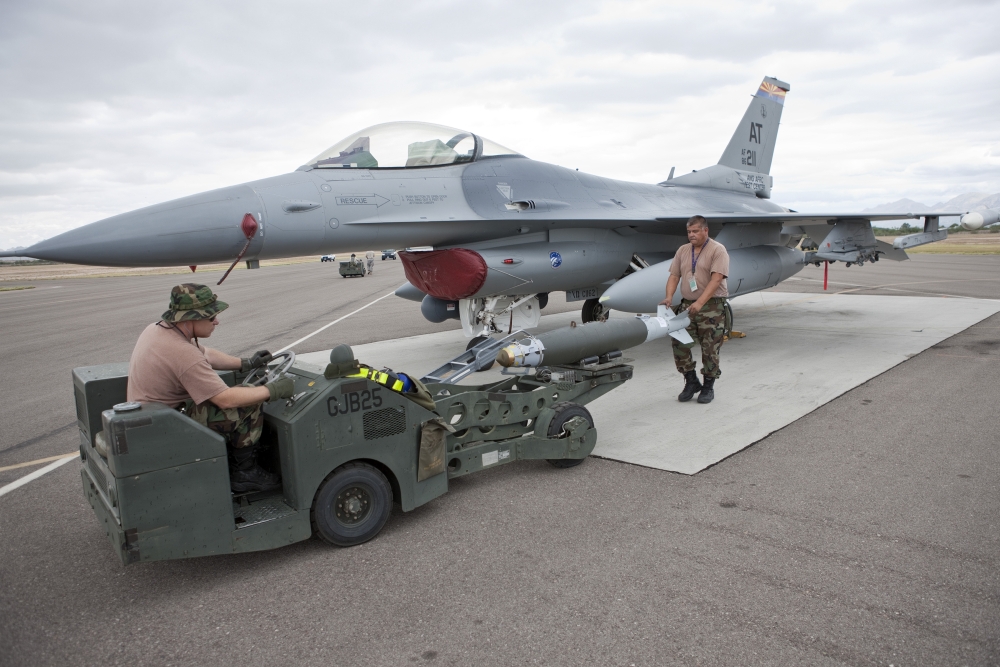 Weapons loaders prepare to load a GBU38 JDAM on an F16 Stretched