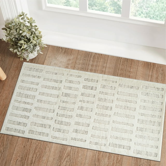 Modern beige cream indoor area rug with abstract rectangular design placed on wooden floor by a potted plant and large windows.