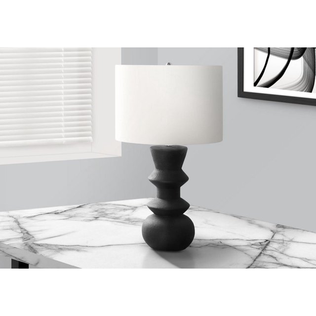 Contemporary black ceramic table lamp with sculpted base and ivory cream drum shade on marble tabletop