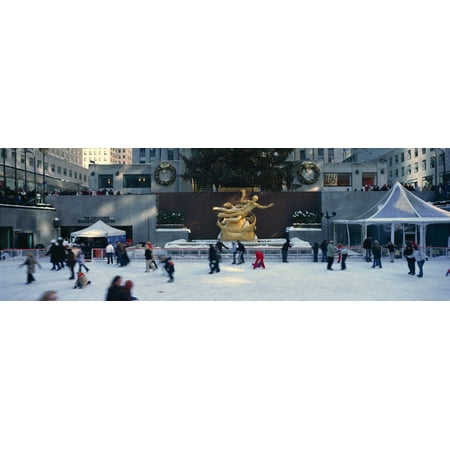 Rockefeller Square and ice skating rink and ice skaters at Christmas time with snow in mid-town Manhattan NY Stretched Canvas - Panoramic Images (27 x