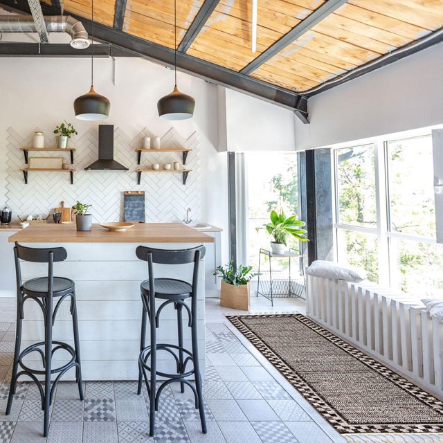 ECARPET Southwestern Quattro Collection rug placed in a sunlit kitchen hallway featuring modern black bar stools, wooden countertop, and decorative plants.