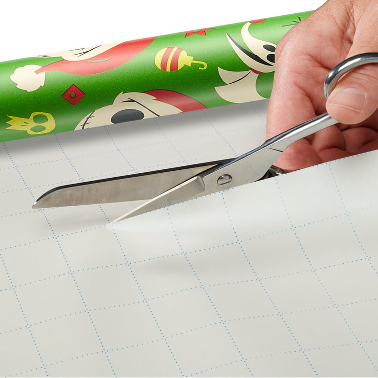 Person using scissors to cut a roll of plain white wrapping paper