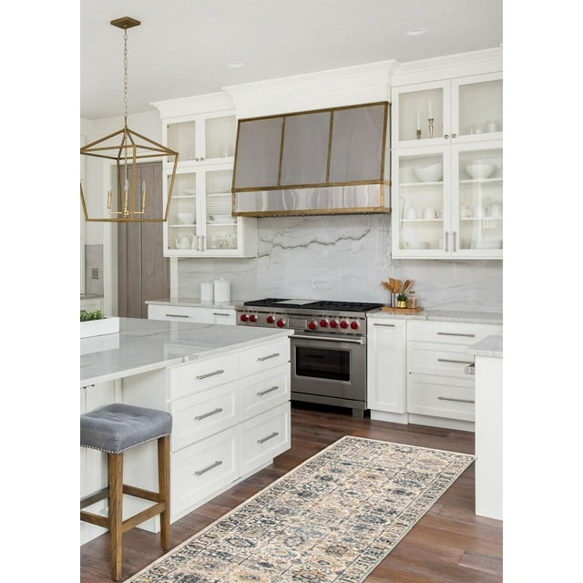 Traditional vintage style Bolivia Yalameh area rug with intricate neutral and blue patterns on wooden floor of a modern white kitchen.