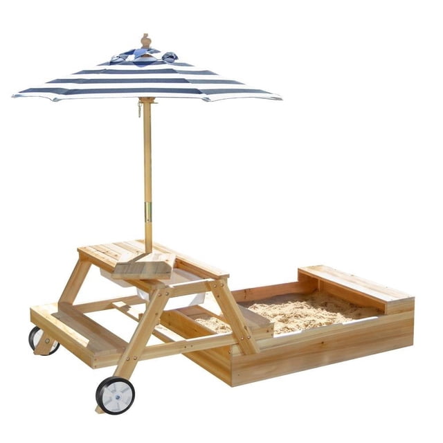 caja de arena teamson 2 en 1 Mesa para picnic y caja de arena de madera clara con banco integrado, tapa abatible que se convierte en superficie de mesa, sombrilla a rayas azul y blanca, ruedas para transporte y compartimento con arena para juego sensorial; también suele usarse como mesa de actividades al aire libre.