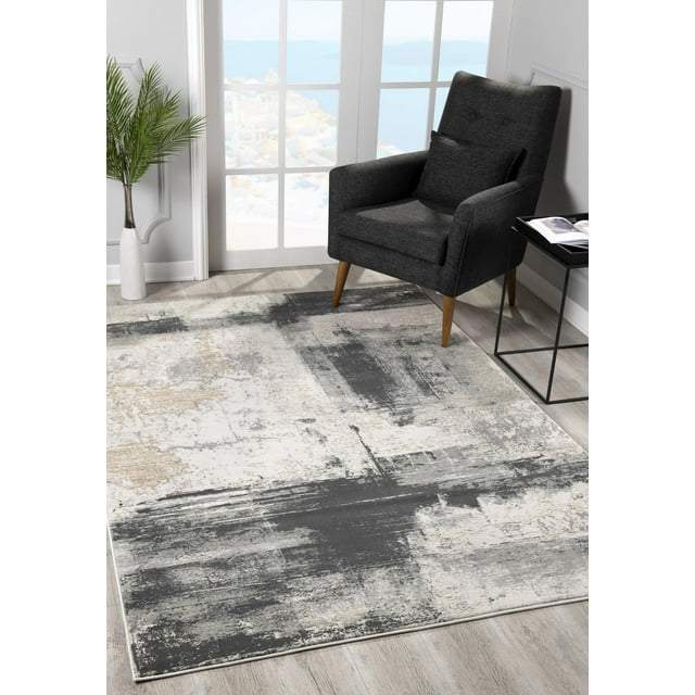 Runner area rug from Rug Branch Silvia Collection featuring modern abstract distressed patterns in gray, beige, and white tones on light wood floor beside a dark gray armchair.