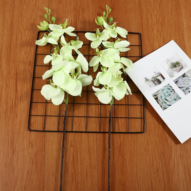 Orquídea de tela en tono verde claro, ideal para decoración interior y exterior, resistente al agua y eco-amigable, disponible en varios modelos, perfecta para bodas, fiestas y celebraciones.