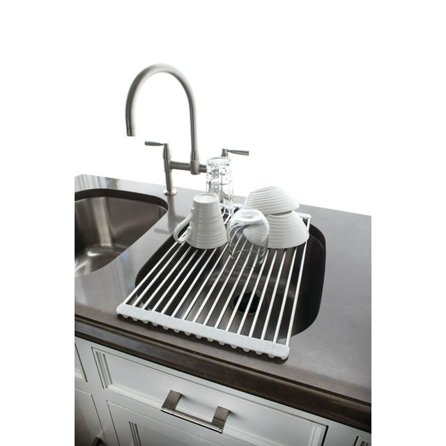 JOIE roll-up dish drainer positioned over a kitchen sink holding white cups and clear glasses to dry.