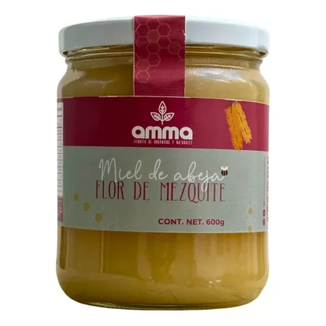 miel pura de abeja flor de mezquite 600g virgen AMMA — Frasco frontal de vidrio, vista de frente; etiqueta roja y gris que indica “Miel de abeja Flor de Mezquite” y peso 600g, tapa blanca y sello vertical rojo; miel de color claro con variación visible según la cosecha; adecuada para endulzar té o recetas caseras.