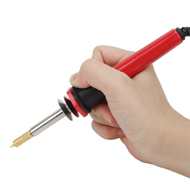 pluma de grabado eléctrica, pluma de pirograbado, kit de soldador eléctrico para quema de madera antioxidante plástico para metal vidrio madera para metal Herramienta de pirograbado de mano con cuerpo cilíndrico rojo y mango negro, vista en 3/4 sostenida por una mano; punta metálica dorada intercambiable montada en vaina de acero inoxidable con placa deflectora circular y cubierta de silicona en el cable. Incluye cinco cabezales reemplazables según necesidad; también es adecuada para detalles finos en vidrio.