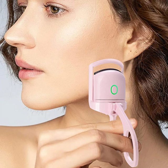 enchinador de pestañas buytiti con indicador de luz de calor, rizador eléctrico blanco en vista 3/4 junto al ojo de una mujer; cuerpo compacto de ABS con almohadilla de silicona visible y botón con luz verde, diseño ergonómico plegable y gancho para bolso, tamaño de viaje (13×6.5×4 cm) y cable tipo C incluido; suele usarse también para dar forma rápida a pestañas postizas en salida.