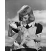 Girl feeding milk to a puppy from a baby bottle Poster Print