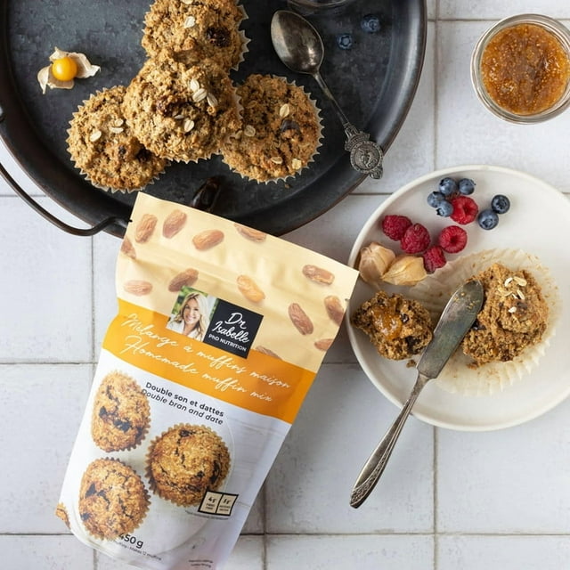 Dr Isabelle Mélanges pour muffins et Biscuits - Lot de 6, Incluant 2 Mélanges de muffins Double Son aux Dattes, 2 Mélanges de Gruau aux Canneberges et au Chia, et 2 Mélanges de Chocolat et de Chia pour Biscuits. l'Image Affiche un Sac de Mélange Dr Isabelle's sur une surface Carrelée, Entouré de muffins Fraîchement Cuits sur un Plateau et une Assiette avec un Muffin Servi avec des Baies Fraîches et de la Confiture. le Produit Est Riche en Fibres, Faible en Gras, et Fait avec des Ingrédients Propres et Simples pour une Cuisson