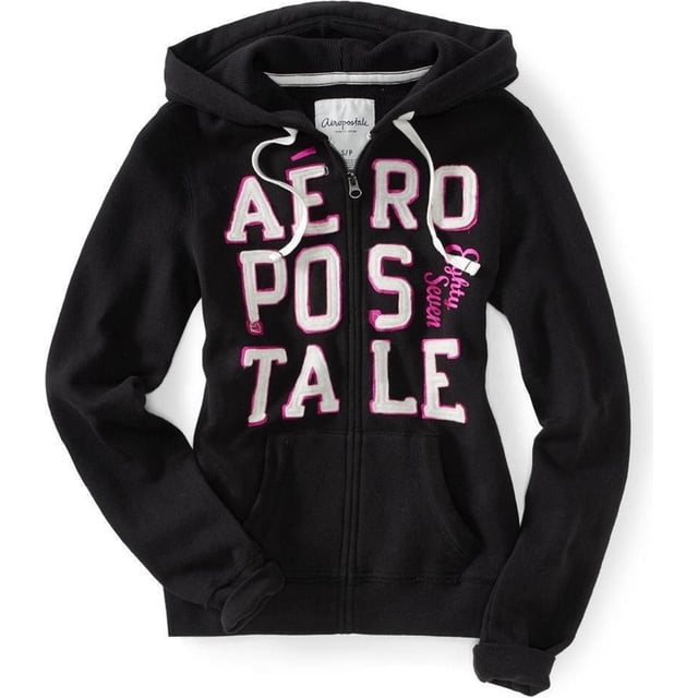 sudadera con capucha y cremallera completa aeropostale aero stacked 87 para mujer negro grande Sudadera negra con capucha y cierre frontal completo, vista frontal centrada; bolsillos tipo canguro, puños y cintura acanalados. Grandes letras aplicadas "AEROPOSTALE" en blanco con borde rosa y parche con logotipo aplicado en el pecho derecho. Cordones blancos en la capucha y cremallera metálica visible; serigrafías con brillo sobre tejido liso. Fondo blanco, prenda extendida para mostrar forma. También suele usarse como capa cómoda para viajes o salidas informales.