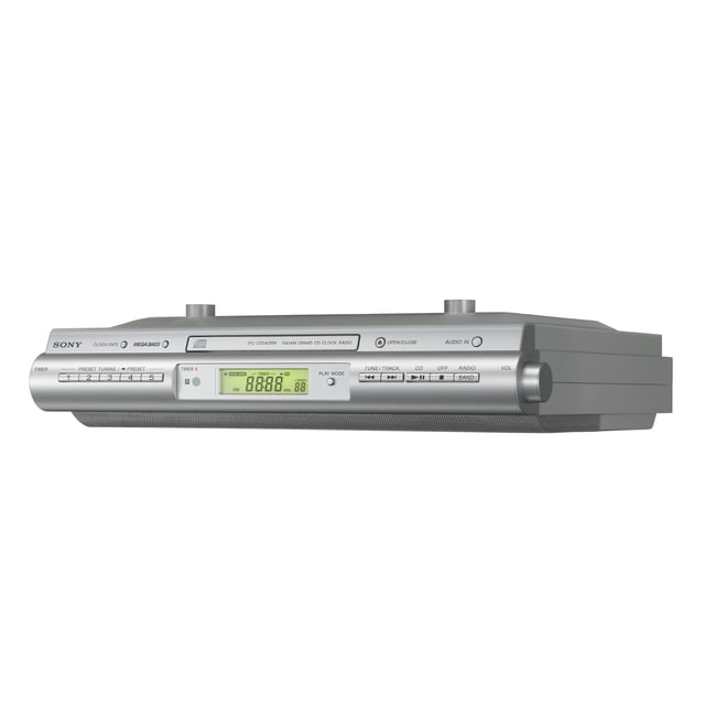 radio reloj sony icfcdk50 para cocina, para instalar bajo gabinete, con reproductor de cd unidad plateada para montaje bajo gabinete con pantalla LCD verde en el frente; bandeja de CD en la parte superior, botones de reproducción y sintonizador digital FM/AM con presintonías, altavoz frontal con rejilla, control remoto magnético y cable de audio integrado; también suele usarse para reproducir CDs de recetas o música mientras se cocina.