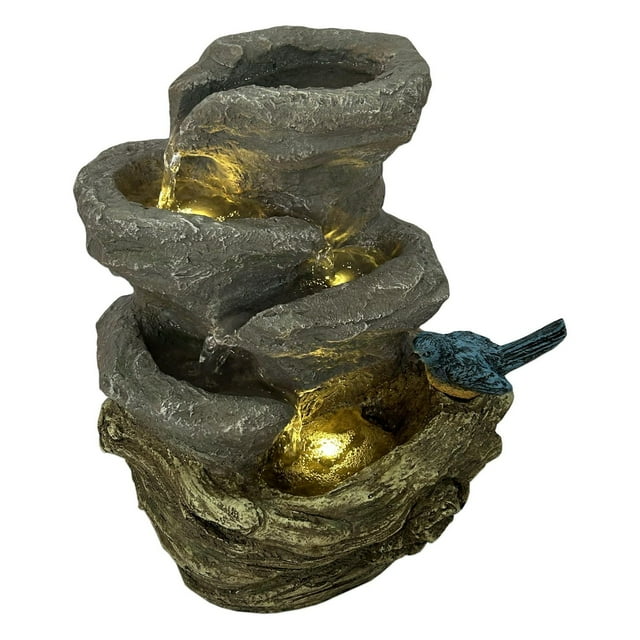 Finch Falls tabletop fountain by Angelo Décor featuring cascading water over stone-like tiers illuminated by warm LED lights and a small blue bird accent.