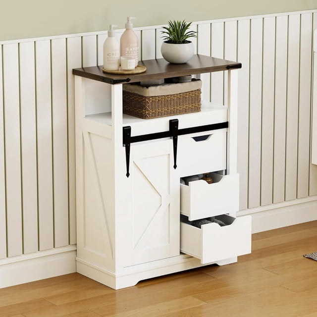 historyli mueble de baño de suelo, con puerta corrediza y 3 cajones, color blanco — Frontal 3/4 de gabinete blanco con tablero superior madera, puerta corrediza tipo granero en riel metálico negro y tres cajones (dos abiertos), estante central abierto con canasta, tiradores empotrados, base elevada sobre piso de madera y pared con paneles verticales.