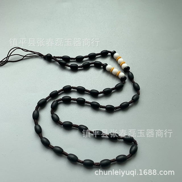 jewelry and jade pendants, jade pendants, guanyin and buddha statue pendants, hand-woven hanging ropes, diy necklaces Cordón de cuentas negras alargadas tejido en hilo marrón con secciones de cuentas blancas y amarillas, dispuesto en espiral sobre fondo gris, primer plano que muestra nudos y cierre ajustable.