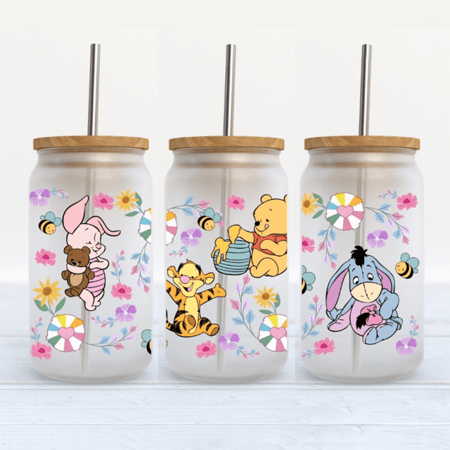 3d uv dtf cup wrap vinilo de transferencia impresión personalizada a todo color ready stick 16oz libbey glass dtf uv cup wraps transfers Tres vasos Libbey 16 oz con tapas de madera y popotes, vistos frontalmente con envolturas DTF UV impresas en película PET y tinta plastisol; motivos infantiles a todo color (cerdito con oso, tigre, Winnie the Pooh con jarra y burro) sobre patrón floral con abejas; diseño y tamaño personalizables para tazas, vasos y botellas.