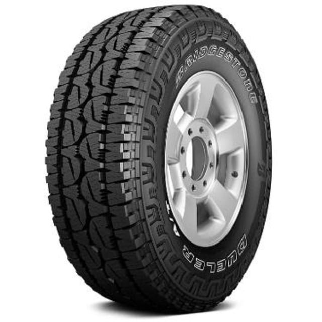 llanta bridgestone dueler a/t revo 3 265/65r17 110 t neumático todo terreno, vista 3/4 frontal sobre rin 17; banda de rodamiento agresiva con bloques escalonados y canales profundos, letras Bridgestone y DUELER visibles en el costado, diseño imponente y apto para conducción desafiante en off-road. Su tamaño 265/65R17 está indicado en el flanco.