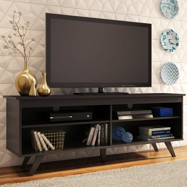 Madesa TV Stand Entertainment Center in black, designed for TVs up to 65 inches. Features a modern wooden design with four spacious shelves for media storage and a wide tabletop. Includes cable management holes at the back for organized wiring. Made from durable, eco-friendly engineered wood. Shown in a living room setting with decorative items and a TV on top.
