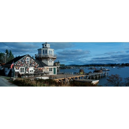 This is a lobster village in New England There is a long pier with lobster traps stacked up at the end It is the southwest harbor with a large fishing house with a tower There are fishing buoys attach