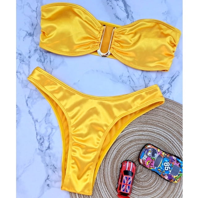 traje de baño europeo y americano sexy en forma de u, traje de baño de hierro en v, bikini para mujer Amarillo bandeau con anilla metálica en U en el centro y braga de talle medio en tejido brillante, vista cenital sobre fondo tipo mármol con sombrero de paja y accesorios de playa; a menudo usado como conjunto de baño para días de playa.