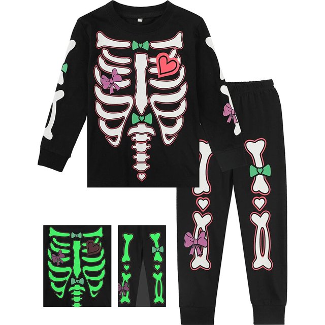 pijama de halloween para niños y niñas, conjunto de pijamas de esqueleto que brillan en la oscuridad, pijamas de carnaval para niños, pijamas de fiesta infantil conjunto negro de 2 piezas con camiseta de manga larga y pantalón largo; estampado frontal de costillas y columna en blanco con lazos y corazones rosa y verde, huesos impresos en mangas y piernas, detalle que brilla en la oscuridad mostrado en recuadros, corte recto, cuello redondo y cintura elástica.
