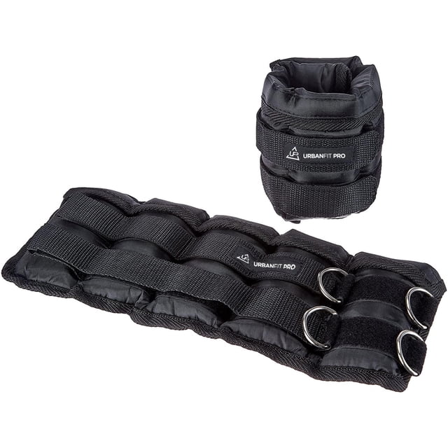 tobilleras par de polainas tobillos 2kg pesos para tobillos ajustable negro unitalla par de polainas UrbanFit Pro negras; una enrollada y otra extendida mostrando acolchado rectangular, cierre de velcro ancho, tres anillas metálicas y tiras de refuerzo textiles con etiqueta cosida. Peso 2 kg por pieza; aptas para añadir resistencia en ejercicios de piernas, glúteos y abdomen bajo; a menudo se usan también para entrenamiento en casa.