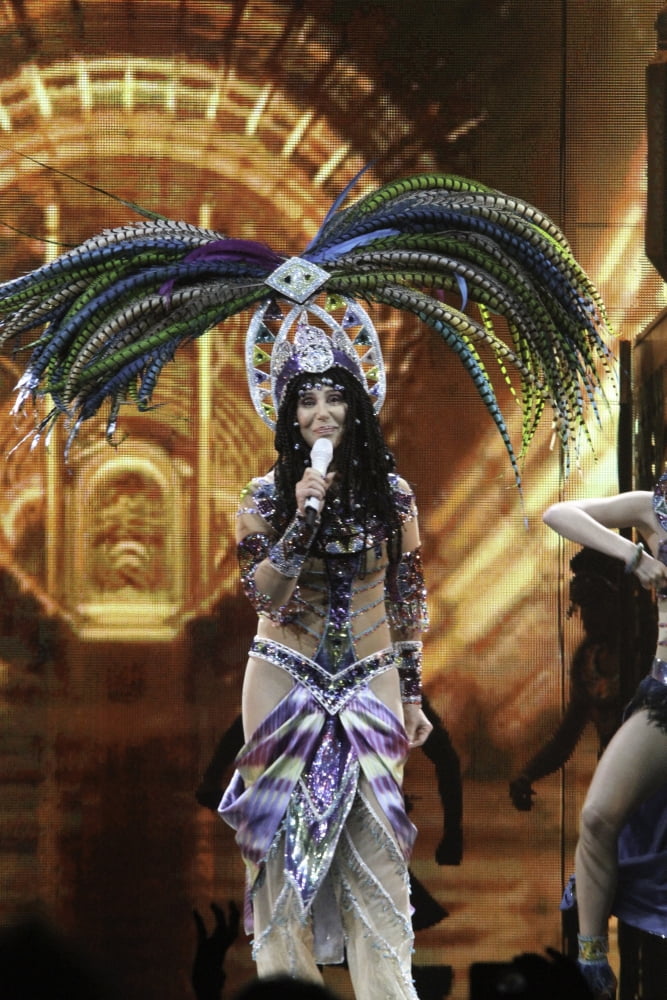 Cher wearing a feather headdress performing in the Dressed To Kill tour