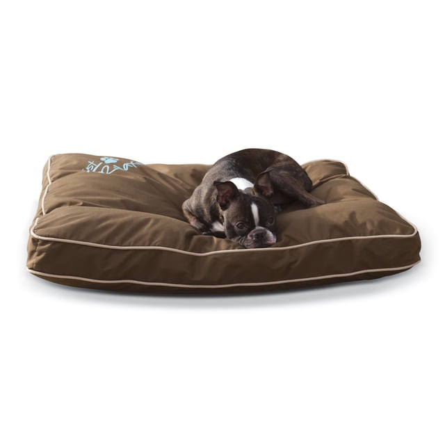 cama interior y exterior just relaxin´chocolate para perro cama rectangular chocolate K&H con borde acolchado y costuras visibles, relleno canalizado en secciones que no se apelmaza, funda removible resistente al agua con tratamiento UV, perro pequeño recostado sobre fondo blanco; también suele usarse para crear una zona de descanso portátil en viajes cortos.