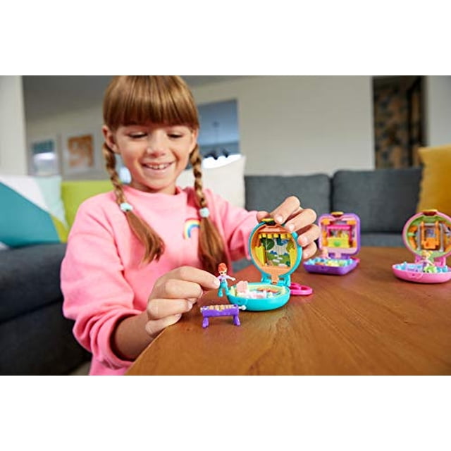 polly pocket pocket world owlnite campsite compact with diversion revels, micro polly y shani compacto de campamento multicolor Pocket World abierto en vista frontal; estuche circular de plástico con escena de bosque y árbol, incluye dos micro muñecas Polly y Shani y accesorio de bote, varios compactos desenfocados sobre mesa de madera en sala. Adecuado para juego portátil.