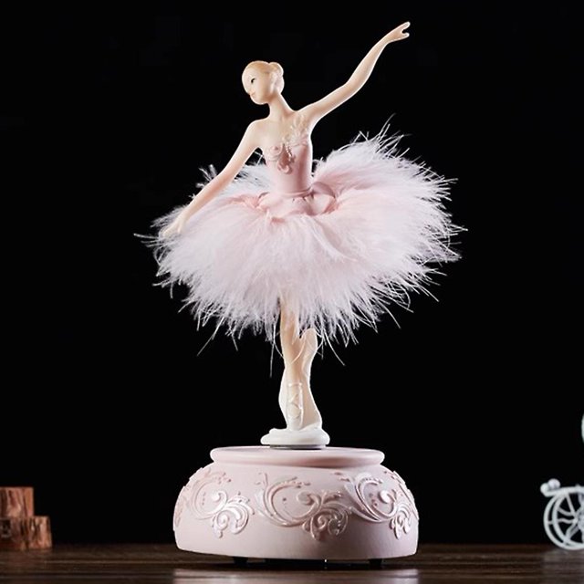 ballerina music box dancing girl swan lake carousel with feather for birthday gift Rosa resin caja musical con bailarina giratoria y falda de plumas, 10 x 10 x 23 cm; toma frontal sobre fondo oscuro que muestra la base tallada con motivos florales y el mecanismo de cuerda.