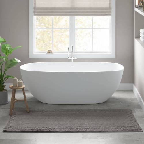24x60-inch 100% cotton tufted bath rug in charcoal, featuring a heavyweight 3000 GSM construction and a medium 0.5-inch pile. The rug is fully reversible and machine washable for easy care. Displayed in a modern bathroom setting with a freestanding white bathtub, a wooden stool, and natural light from a window.