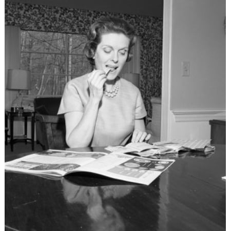 - Mid adult woman reading magazine at home Poster Print