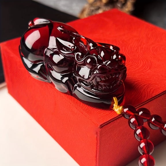 Hand-carved stone amulet with red agate Pi Xiu, featuring exquisite craftsmanship and a tassel, designed to attract wealth and bring good fortune according to Feng Shui principles.,Black
