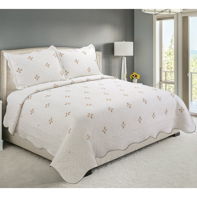 Ultra soft white coverlet bedspread and quilted sham set featuring embroidered gold floral pattern, displayed on beige upholstered king-size bed in bright modern bedroom.