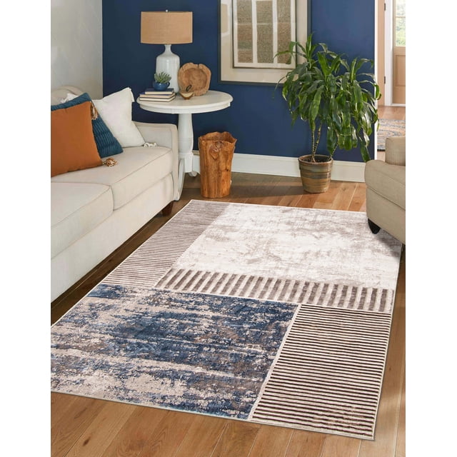 Modern ECARPET Monica area rug featuring abstract blue and beige blocks with brown stripes on hardwood floor between sofas in a cozy living room.